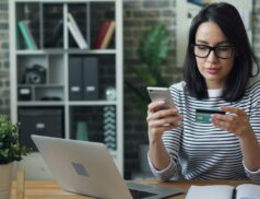 Woman sitting in front of the laptop with her debit card, wanting to buy something online, maybe she wants to improve her online shopping experience